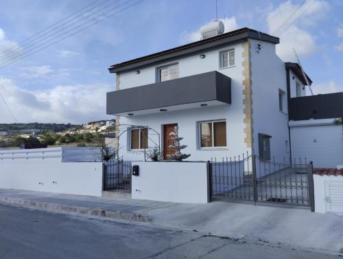 uma casa branca com uma cerca à frente. em Michael Angelo Villa em Pafos