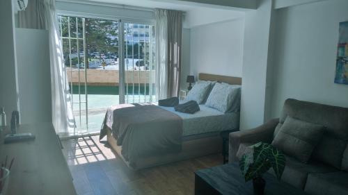 una camera da letto con un letto, un divano e una finestra di Serenity Chic Apartment City Center with FREE Wifi BY NAMASTE ELITE a Torremolinos