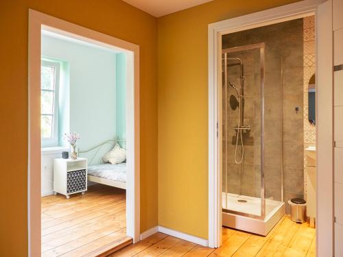 La salle de bains est pourvue d'une douche et d'une porte en verre. dans l'établissement Świerkowe Przysiółki, à Sośnina