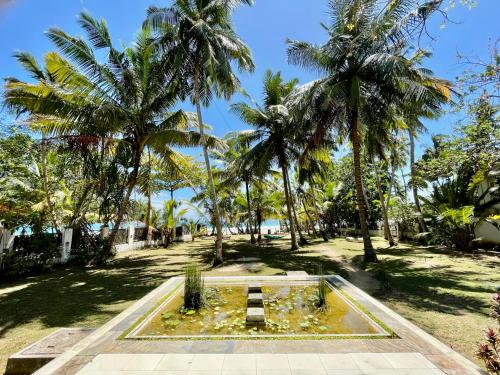 a fountain in the middle of a park with palm trees at Isana Beach House in Tangalle