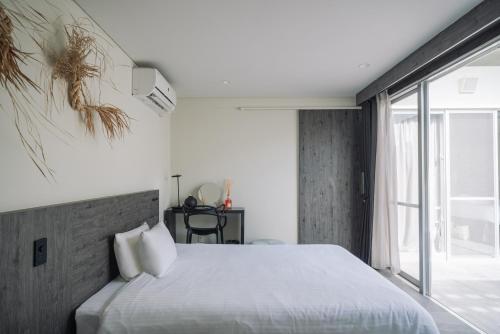 sypialnia z dużym łóżkiem i dużym oknem w obiekcie Villa Conte w mieście Miyako-jima