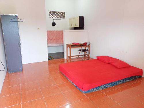Zimmer mit einem roten Bett und einem Tisch. in der Unterkunft GEA Syariah in Bengkeng