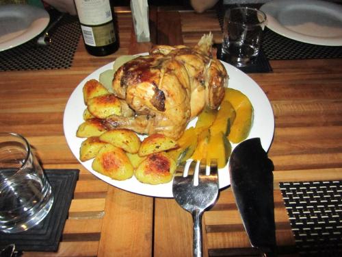 a white plate with a chicken and potatoes on a table at Isana Beach House in Tangalle