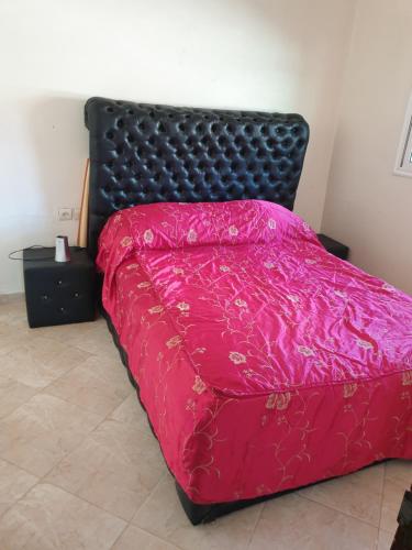 a bedroom with a bed with a pink comforter at Logement a 8mn de mehdia in Kenitra