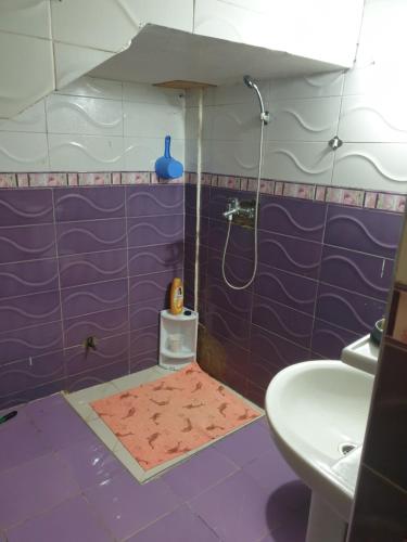 een paarse badkamer met een douche en een wastafel bij Logement a 8mn de mehdia in Kenitra