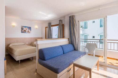 een slaapkamer met een blauwe bank en een bed bij Apartamentos Bossa Bay - MC Apartamentos Ibiza in Ibiza-stad