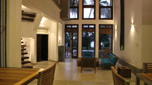 a living room with tables and chairs and windows at Isana Beach House in Tangalle