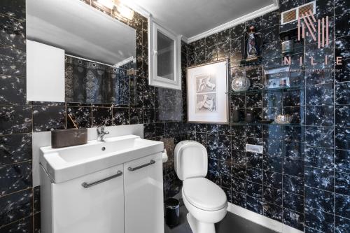 Baño de azulejos negros con aseo y lavamanos en ArtHall, Nilie Hospitality MGMT en Tesalónica