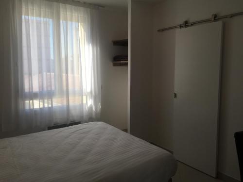 a bedroom with a white bed and a window at Le Logis Dauphinois in Roussillon en Isere