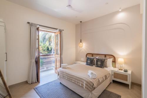ein Schlafzimmer mit einem Bett und einem Balkon in der Unterkunft Elivaas Opalys Luxe 4BHK Villa with Pvt Pool near Baga in Calangute