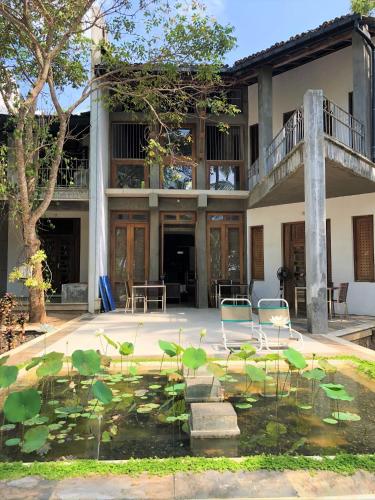 a building with a pond with water lilies in front of it at Isana Beach House in Tangalle