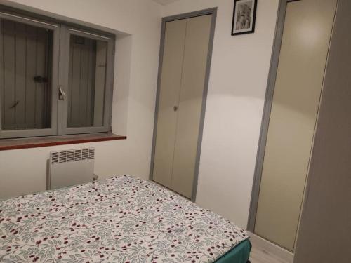 ein Schlafzimmer mit einem Bett, einem Schrank und einem Fenster in der Unterkunft Petite maison de village in Puylaurens