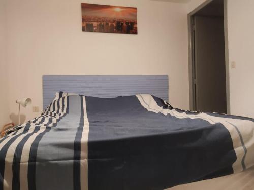 ein Bett in einem Schlafzimmer mit einer blauen und weißen Decke in der Unterkunft Petite maison de village in Puylaurens
