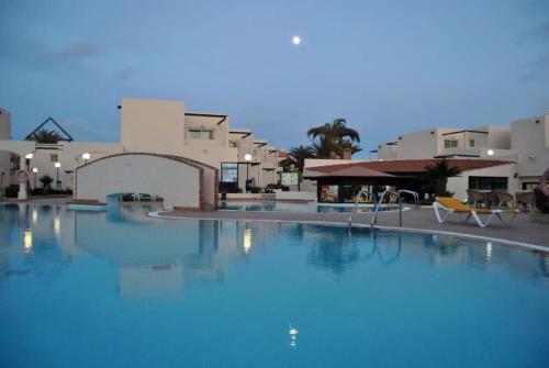 une grande piscine en face de certains bâtiments dans l'établissement Corralejo Suite Pool & Gardens - Alisios Playa, à Corralejo