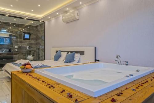 ein großes Bett mit einer großen Badewanne in einem Schlafzimmer in der Unterkunft Villa Ortaç 4 Doğa İçerisinde, korunaklı villa in Kaş