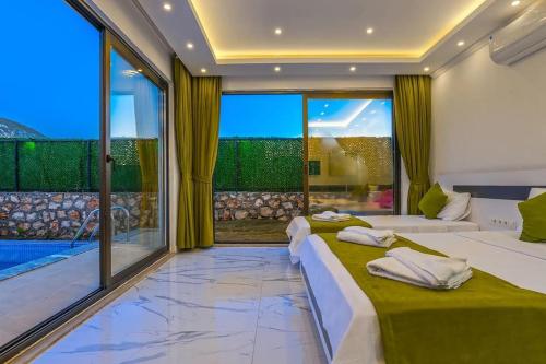 2 Betten in einem Zimmer mit einem großen Fenster in der Unterkunft Villa Ortaç 4 Doğa İçerisinde, korunaklı villa in Kaş