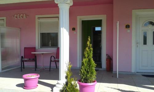 a pink house with a white pillar and a table at Guest House Ceca in Melenci