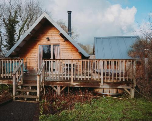 a log cabin with a large deck and a porch at Domaine de la Fauvriere in Sainte-Honorine-de-Ducy