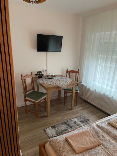 a dining room with a table and chairs and a television at Airport Jazmin Guesthouse in Vecsés