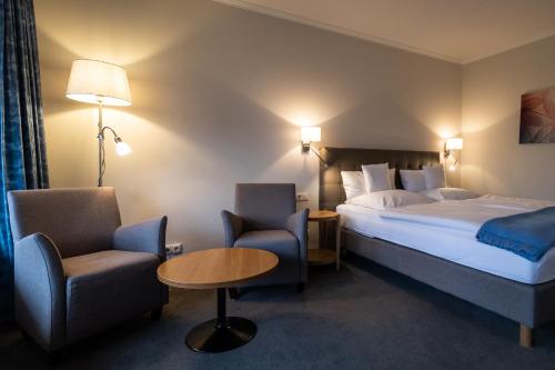 Habitación de hotel con cama, mesa y sillas en VitalHotel Ascona, en Bad Bevensen