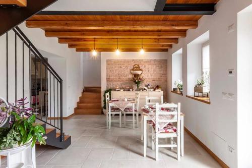 B&b La Casa di Elsa في Polcenigo: مطبخ وغرفة طعام مع طاولات وكراسي بيضاء
