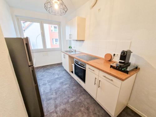 a kitchen with white cabinets and a black refrigerator at Apartment beim Theater in Hildesheim