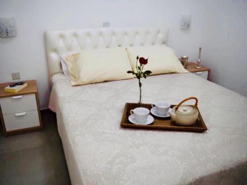 a tray with two cups and a flower on a bed at Riverside Suite in Kalopanayiotis