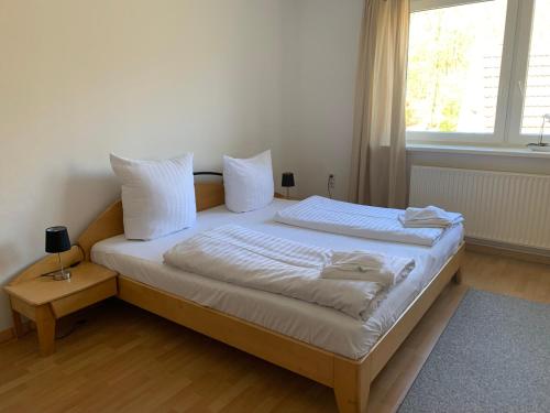 a bedroom with a bed with white sheets and a window at Landhotel Cafe Prälank in Neustrelitz