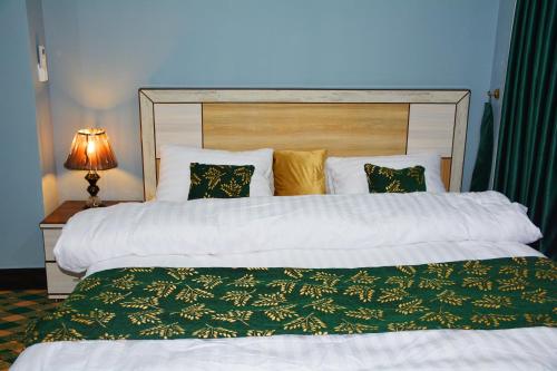 a bedroom with a large bed with a green blanket at Khyber Guest House Swat in Saidu