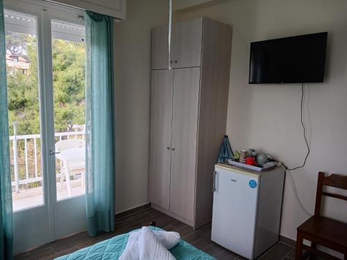 um quarto com uma cama, uma televisão e uma janela em FIORE ROOMS em Akrotiri