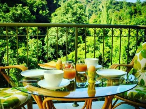 a glass table with cups and drinks on a balcony at Riverside Suite in Kalopanayiotis