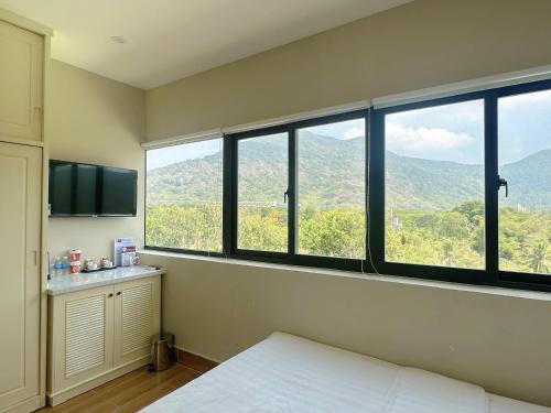 a bedroom with large windows with a view of a mountain at Maya Hotel 2 in Con Dao