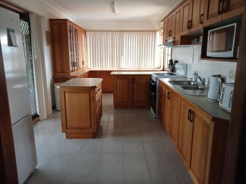 a kitchen with wooden cabinets and a sink and a stove at Boyle's Beach House - Fully furnished 3 Bedroom home. Secure parking. in Nambucca Heads
