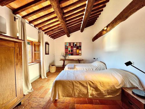 1 dormitorio con 2 camas en una habitación con techos de madera en Masseria di Matraia, en Matraia