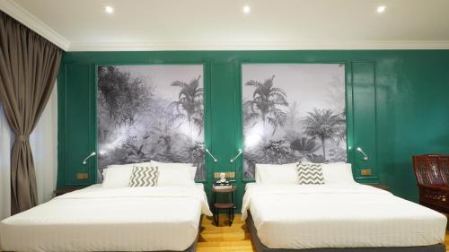 2 posti letto in una stanza con pareti verdi e palme di Kimberley Boutique Hotel a George Town