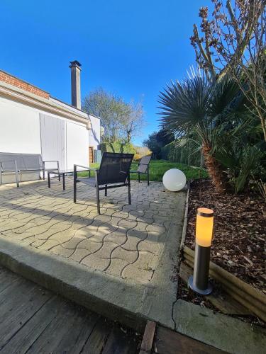 a patio with two chairs and a white building at Scarpe House - Garage - Jardin - Wifi - Douai in Douai