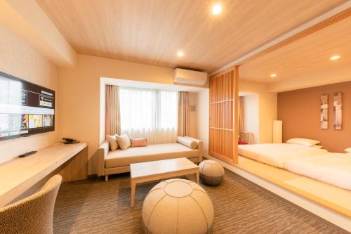 柏市にあるホテル・トリフィート柏の葉のベッド2台とソファが備わるホテルルームです。