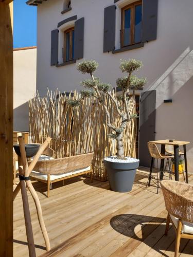 a patio with two chairs and a table and bonsai trees at Intense Boutik-Hôtel in Port-Vendres