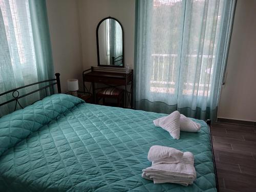 um quarto com uma cama verde e toalhas em FIORE ROOMS em Akrotiri