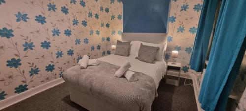 a small bedroom with a bed with blue flowers at Ainslie St by Prestige Properties SA in Barrow in Furness