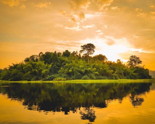 an island in the middle of a lake at sunset at Gibbon Singing Home Stay in Quan Tom