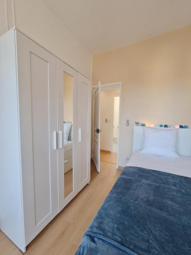 a white bedroom with a bed and a blue rug at Scarpe House - Garage - Jardin - Wifi - Douai in Douai
