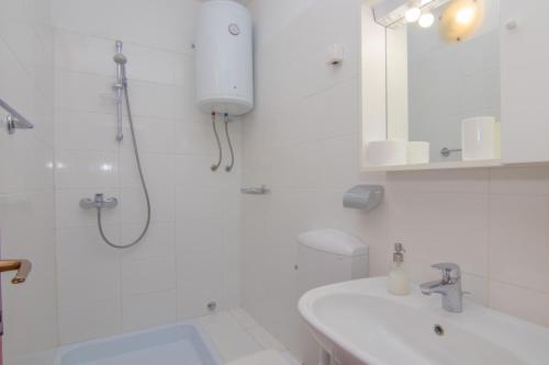 La salle de bains blanche est pourvue d'une douche et d'un lavabo. dans l'établissement Apartments Dunato Nedeljko, à Šilo