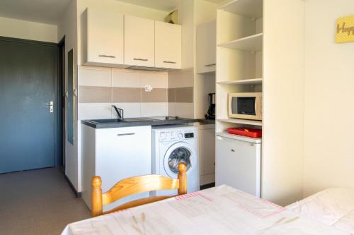 uma cozinha com uma máquina de lavar roupa e um micro-ondas em Appartement T1 à 300m des thermes de Barbotan em Barbotan-les-Thermes