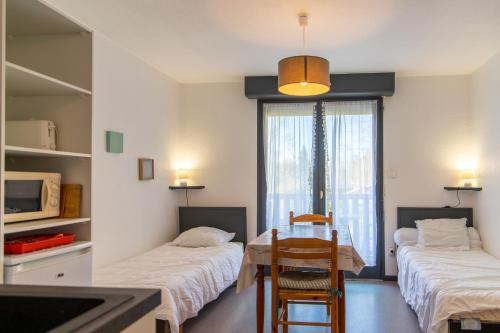 um quarto com duas camas e uma mesa e cadeiras em Appartement T1 à 300m des thermes de Barbotan em Barbotan-les-Thermes