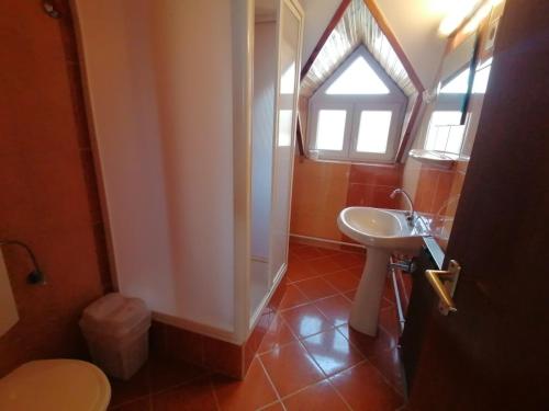 a bathroom with a sink and a toilet and a window at Oleander Vendégház in Tihany