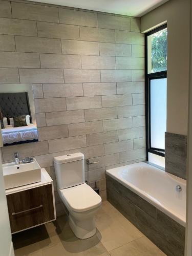 a bathroom with a toilet and a tub and a sink at The Executive - Exclusive Self-Catering Apartments - Ezulwini in Ezulwini