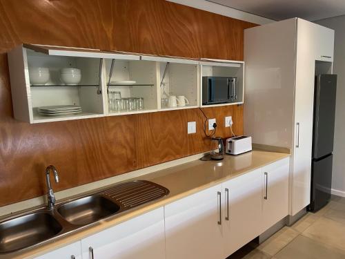 a kitchen with white cabinets and a sink and a refrigerator at The Executive - Exclusive Self-Catering Apartments - Ezulwini in Ezulwini