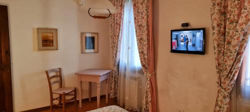 a room with a table and a television on a wall at Hotel Il Casolare in Noghera