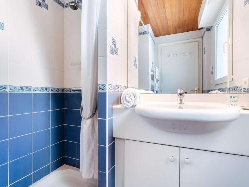 La salle de bains est pourvue d'un lavabo blanc et de carrelage bleu. dans l'établissement Maison 4 pièces avec jardin et piscine chauffée, proche Grande Plage - Carnac - FR-1-477-54, à Carnac